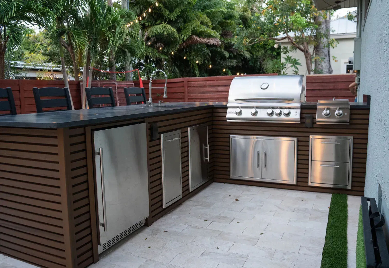 Outdoor kitchen with built-in grill, bar and string lighting in a Keys backyard