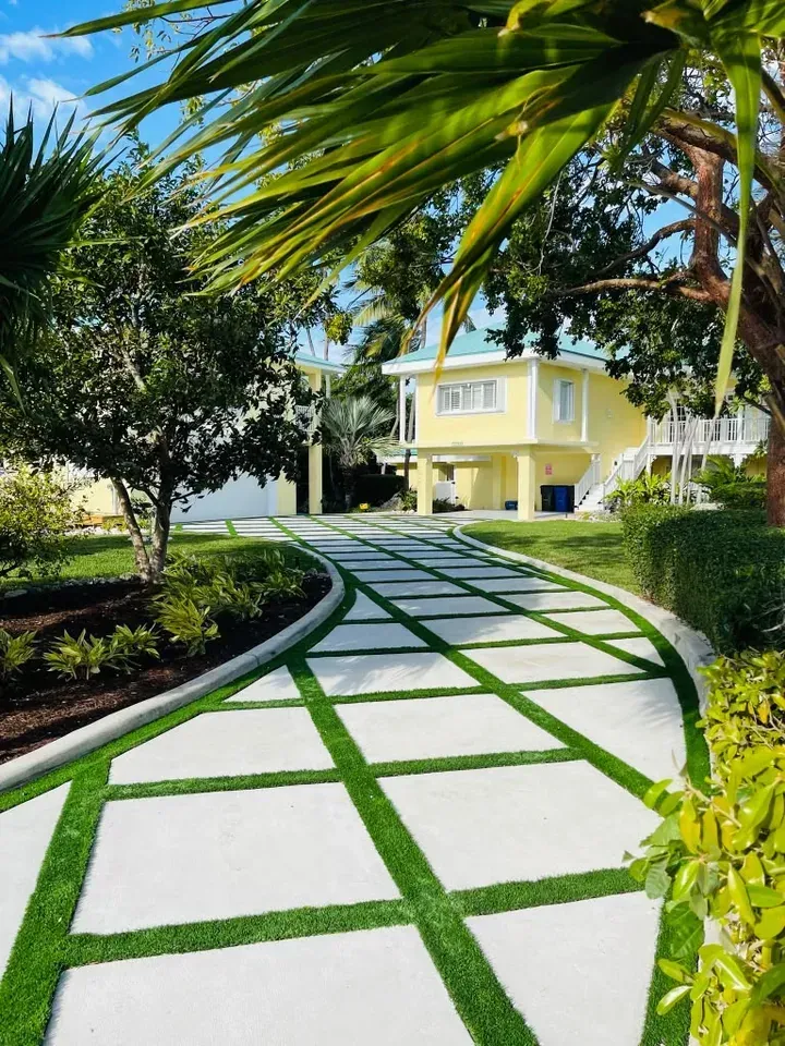 Paver-and-turf ribbon driveway with tropical landscaping at a Key Largo home