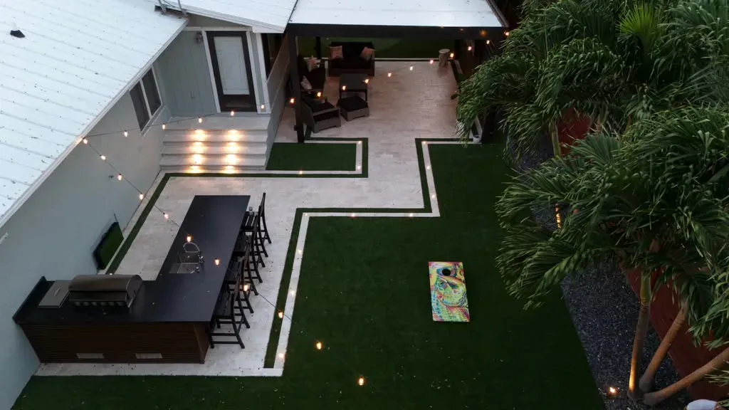 Outdoor kitchen, bar and artificial turf with string lighting at dusk in the Florida Keys